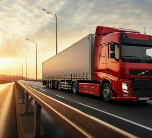 a-cargo-truck-with-a-container-is-seen-driving-across-a-bridge-while-a-semi-truck-with-a-cargo-trailer-follows-closely-behind-photo